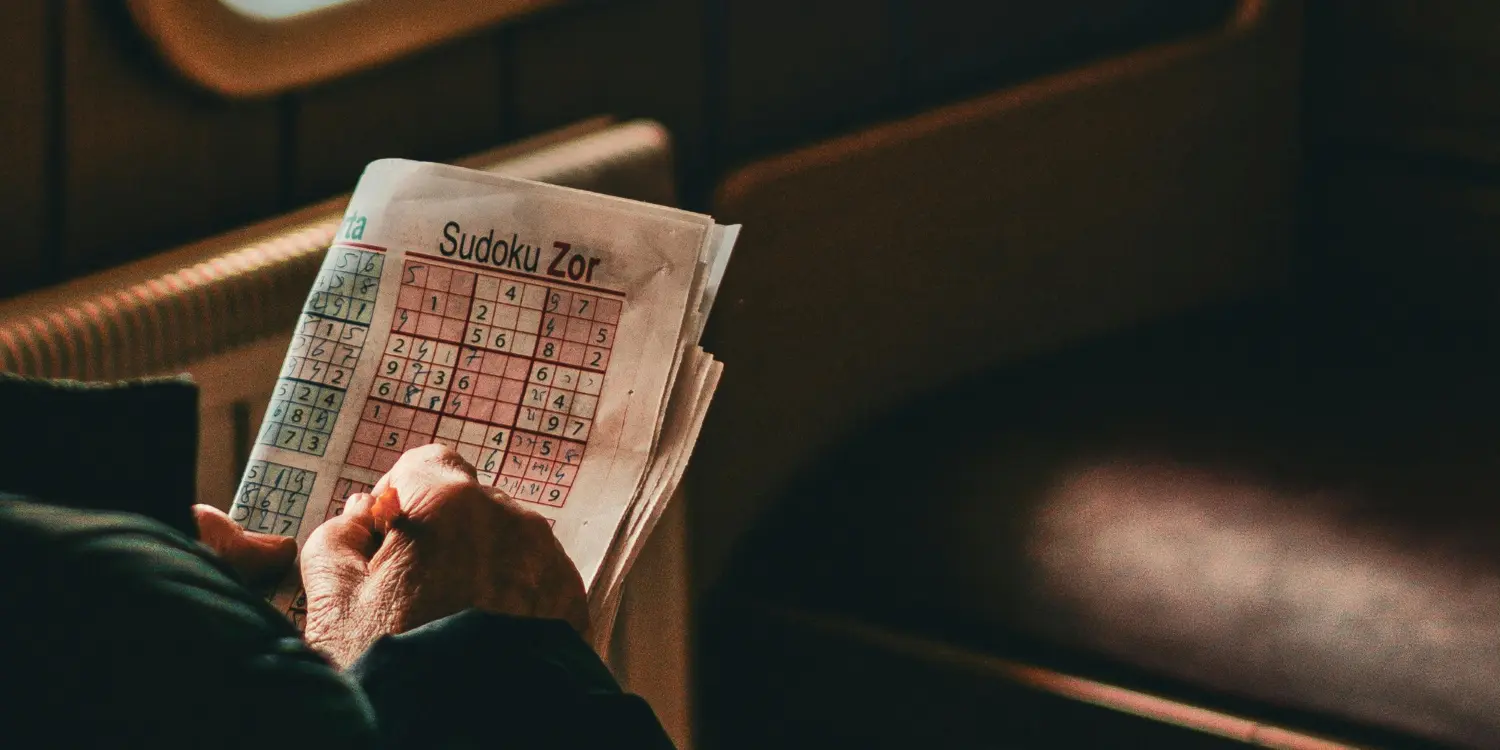 sudoku puzzle being completed in a newspaper